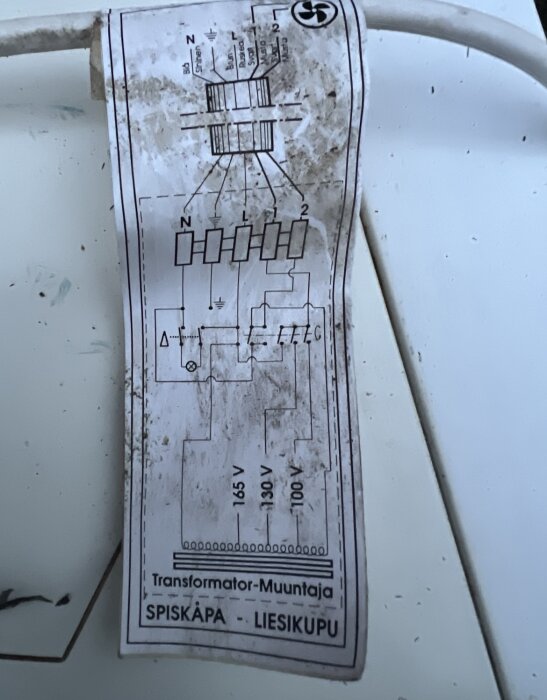 Transformator-schema för spiskåpa med märkningar i volt, smutsig etikett, vit bakgrund. Finns text "Spiskåpa - Liesikupu".