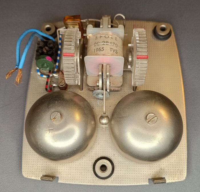 Ringklocka från tidigt sextiotal med dubbla klockor och mekaniska delar, monterad på en fyrkantig platta.