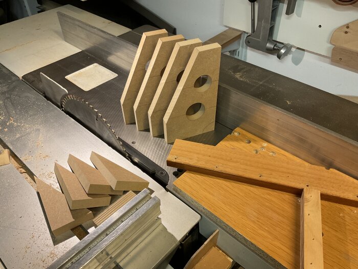 Frästa MDF-delar och vinkelprofiler på en verkstadssåg, redo för montering och användning i byggprojekt.