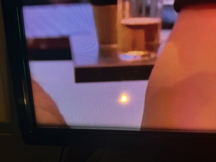 TV-skärm som visar en suddig bild, där en ljusfläck eller något dammliknande syns på ytan.