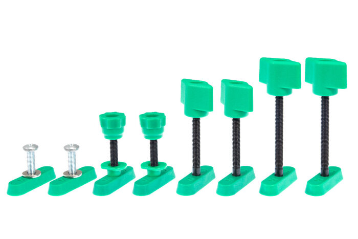 Gröna fastspänningsverktyg i olika storlekar med skruvar, uppställda bredvid varandra på vit bakgrund.