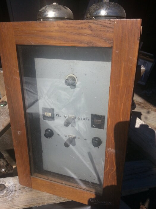 Centralenhet för ett brandlarm från 1941 i träram med metallklockor ovanpå och knappar på framsidan.