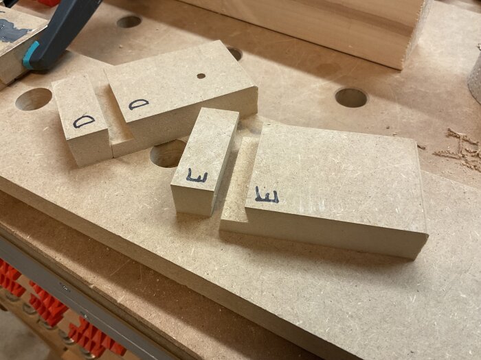 Frästa MDF-bitar märkta med bokstäver, placerade på en arbetsbänk i en verkstad, redo för epoxigjutning.