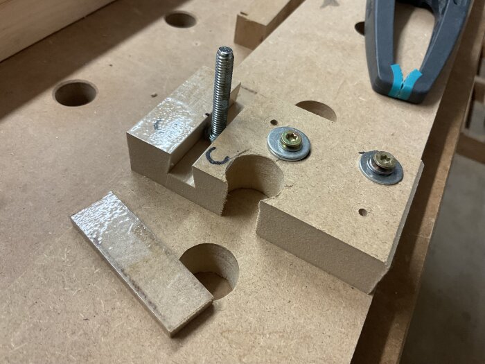 Gjutform i MDF med inslaget packtejp och fastsatt M6-skruv visas på arbetsbänk i verkstad.