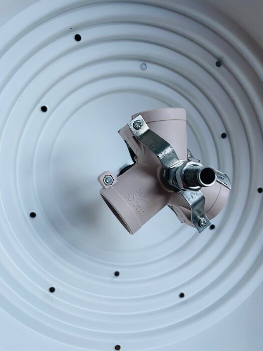 Elektrisk kopplingsdetalj inuti en vit armatur, med flera hål runtomkring, relaterat till en lampa med tre ljuskällor och DCL i taket.