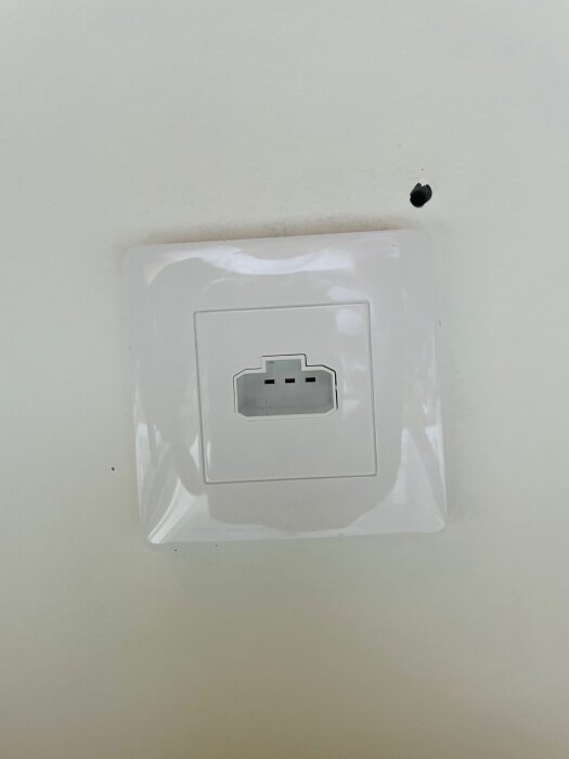 DCL-takuttag på vit vägg med fyra stift, omgivet av en vit plastram.