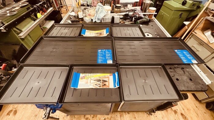 Svart skoskyddssats från Lidl visas på ett arbetsbord i verkstaden, omgiven av verktyg och utrustning.