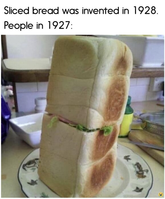 En hel brödlimpa står på tallriken med ett snitt och grönsaker i mitten, humoristisk text om skivat bröd uppfunnet 1928 ovanför.
