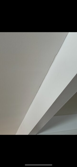 Spricka i kökets tak längs en ljus limträbalk, synlig efter renovering, med potentiell oro för byggstruktur.