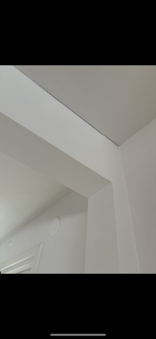 Sprickor längs en limträbalk i ett kökstak, synliga vid övergången mellan tak och balk.