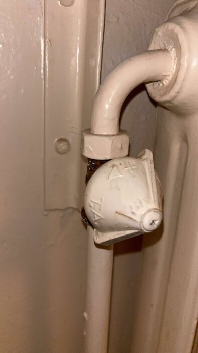 Vredet på ett element med symboler för värmejustering; det är oklart vilket läge som ger mer värme och det läcker vatten vid justering.