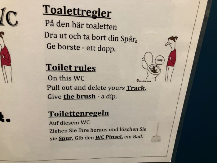 Affisch med toalettregler på danska, engelska och tyska, illustrerad med tecknad bild av person och toalett, text säger att använda borste.