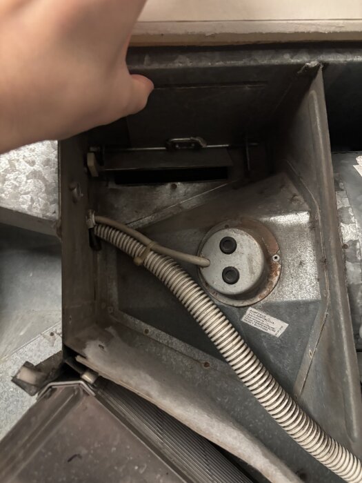 ACF-aggregat med en öppen lucka, sladdar och kondensrör synliga. Hand justerar luckans position för eventuell avfrostning.