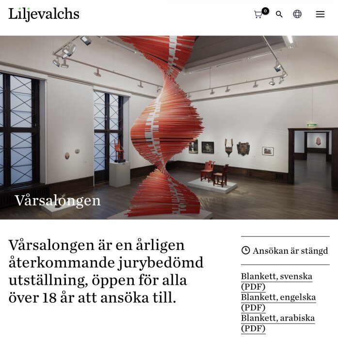 En konsthall med en spiralformad röd konstinstallation och diverse konstverk på väggarna.