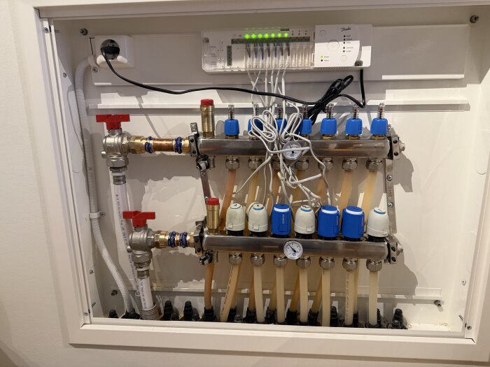 Vattenfördelarskåp med rör och ventiler, där installationen är något sned mot original LK och visar inkommande och returkopplingar.