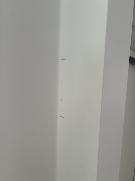 Spricka i vit bärande vägg med bruna markeringar för att följa sprickans tillväxt.