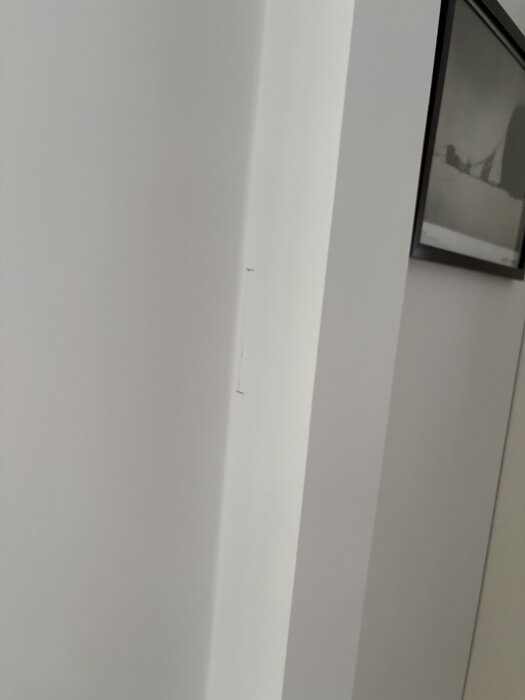 Sprickor och bruna markeringar syns på en vit bärande vägg.