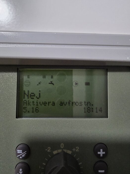 Baksidan av en pump med display som visar "Nej Aktivera avfrostn." och klockan 18:14. Några knappar och en ratt syns under displayen.