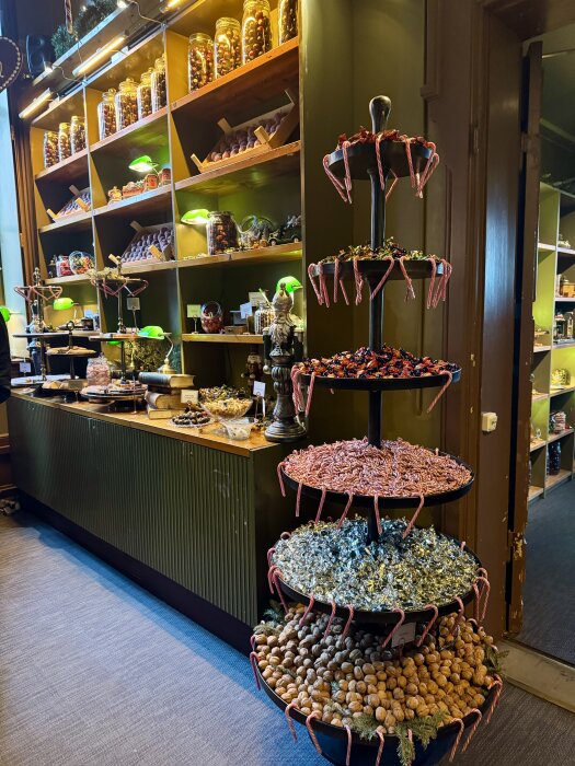 En godisbutik med hyllor fyllda med glasburkar och en flerlagersställning med olika sorters sötsaker och nötter.