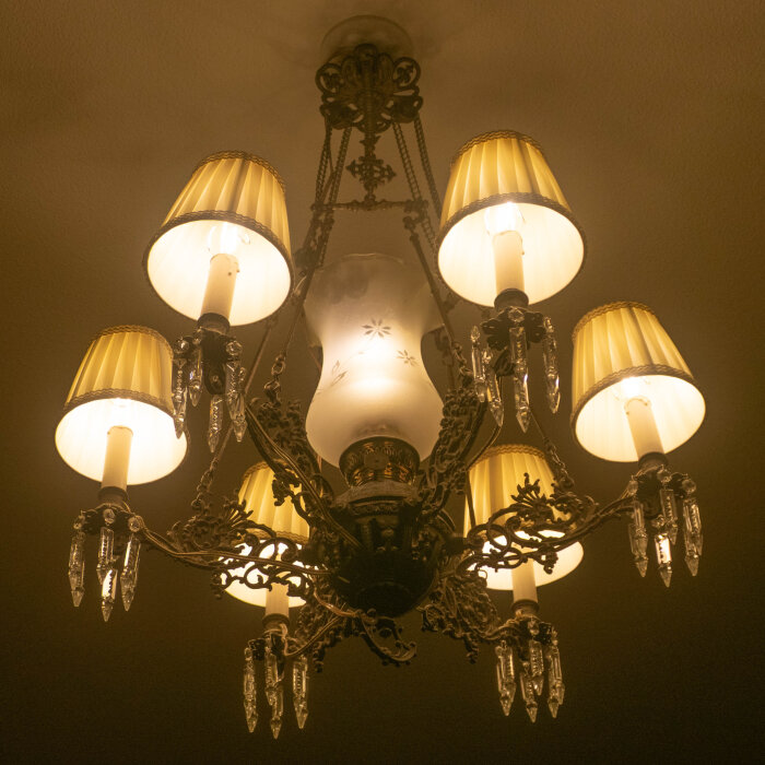 Antik taklampa med sex ljuskällor, guldfärgade detaljer och glaskristaller, det centrala ljuset har adapter för att matcha övriga LED-lampor.