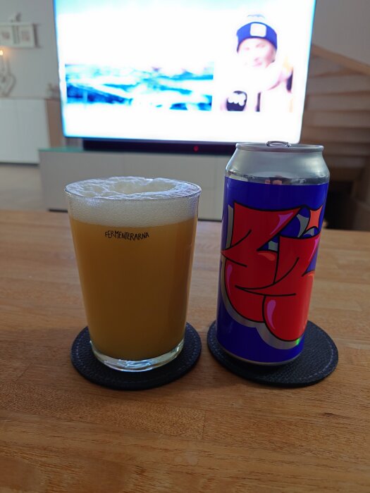 En burk Omnipollo Three Times Three v.7 och ett glas av ölet på ett bord framför en tv.