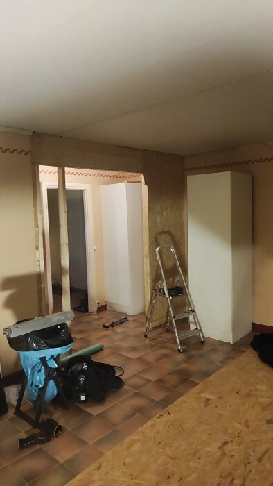 Renoveringsprojekt med OSB-vägg, stege och verktyg i ett rum.