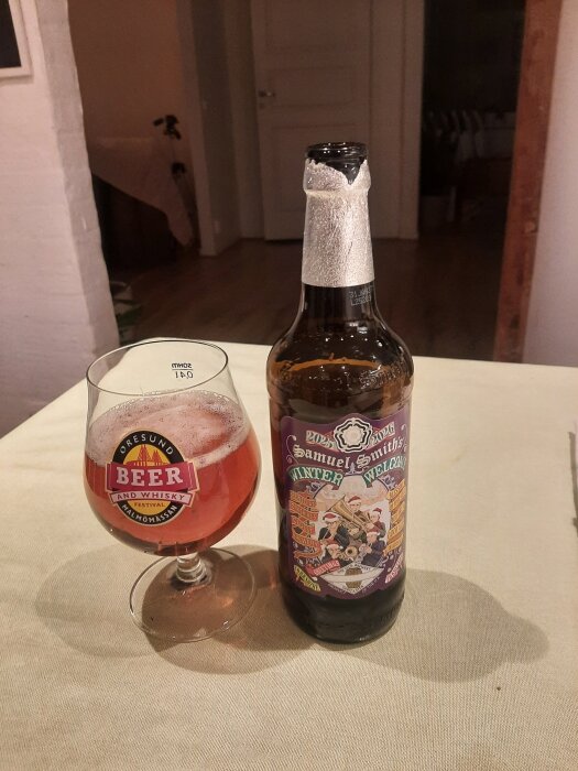 Flaska och glas av Samuel Smith's Winter Welcome Ale på ett bord, del av vintrig byggtrådsdiskussion.