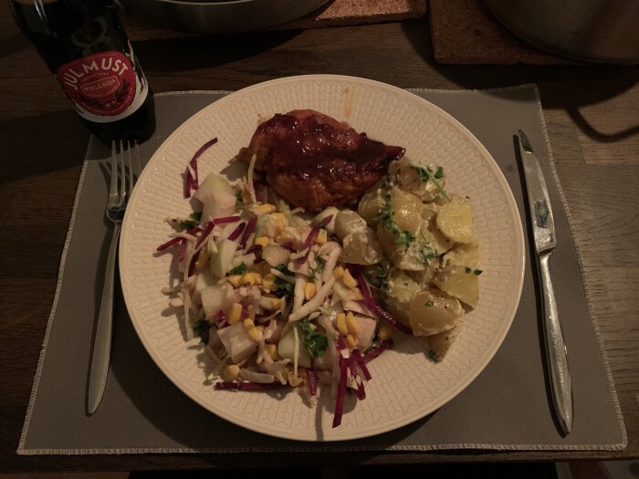 Tallrik med BBQ kycklingfilé, potatis i majonnäs med persilja, råkostsallad och dryckesflaska med julmust.