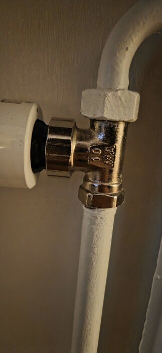 Ventilanslutning med texten "10 MMA" på en metallkoppling mot vägg.