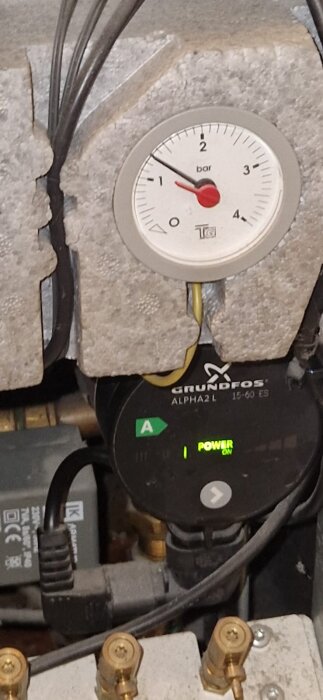 En tryckmätare visar 1 bar och en Grundfos pump med "Power On" indikering syns i ett värmesystem.