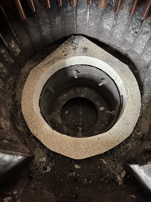 Bild av schakt mellan härd och asklåda med synliga bultar där ett massivt svartjärnroster kan placeras, med plats för luft- och askpassage.