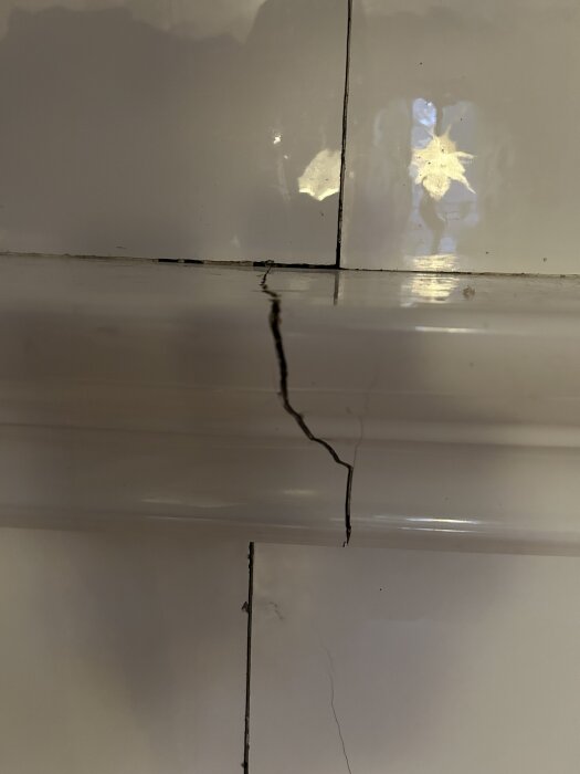 Spricka i kakelugnsplattor, synlig vid hörn, diskuteras huruvida den kan lagas själv.