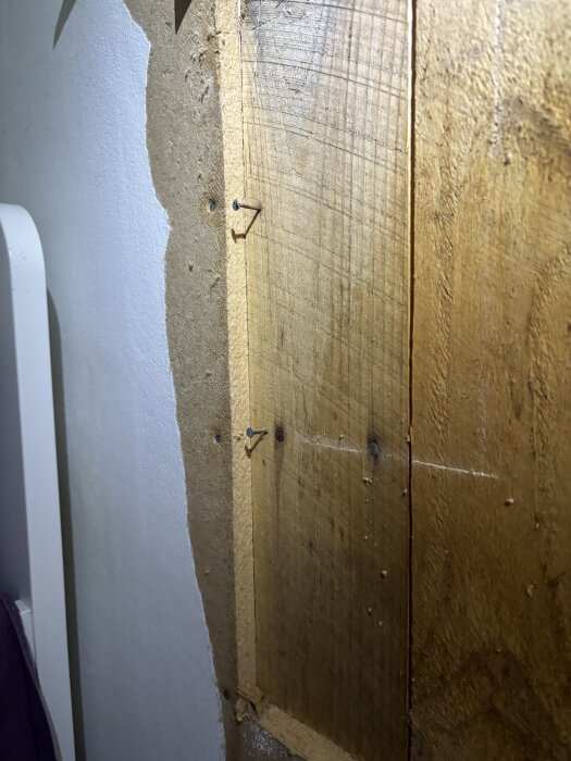 Närbild av en vägg från 1957 med en skiva som kan vara tretex eller masonit, fäst med små spikar.