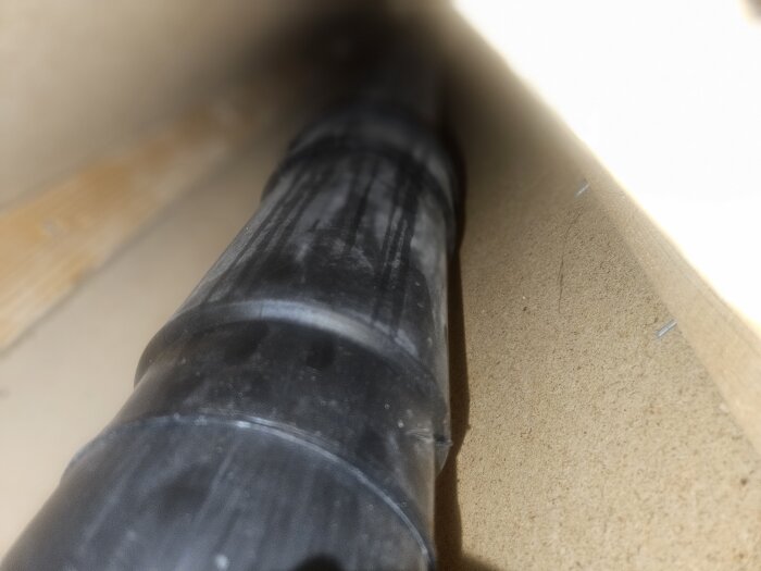 Svart plaströr mellan golvbjälkar i en sutterängvilla från 1970.