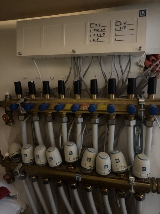 LK vattenburen golvvärmesystem med rör och ventilinställningar synliga, används för att reglera värmen i olika zoner i ett hem.