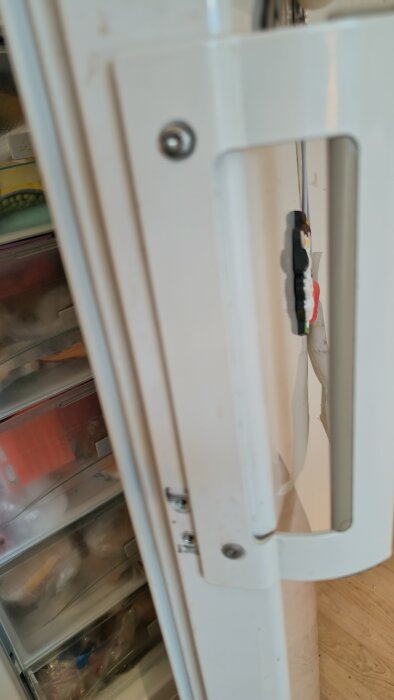 Kylskåpsdörr med stålhandtag från gammal maskin, del av hemmabygge för att ersätta trasiga plasthandtag.