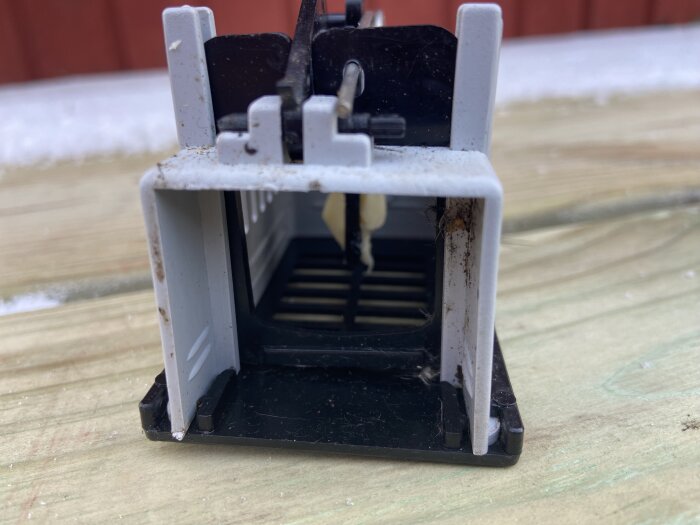 Musfälla i plast med ost som bete, placerad på en träyta.