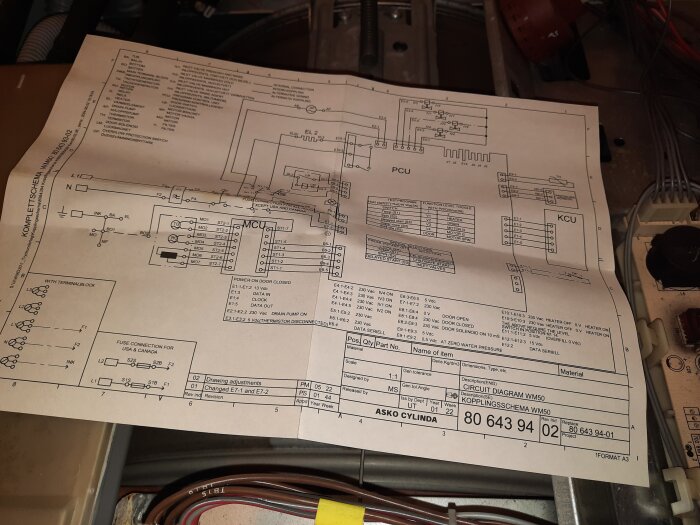Kopplingsschema för ASKO Cylinda WM50 ligger på en arbetsyta, med tydliga elektriska symboler och anslutningar.