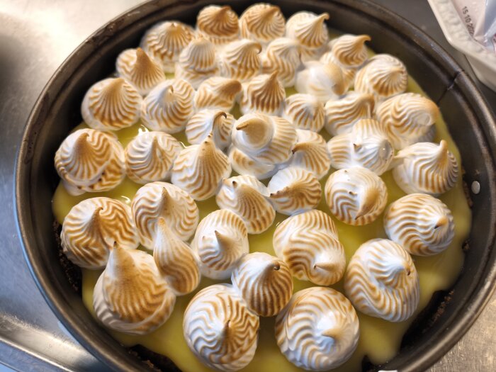 Italiensk marängtoppad cheesecake med digestivebotten och vaniljfyllning i en rund form, bränd för gyllene färg.