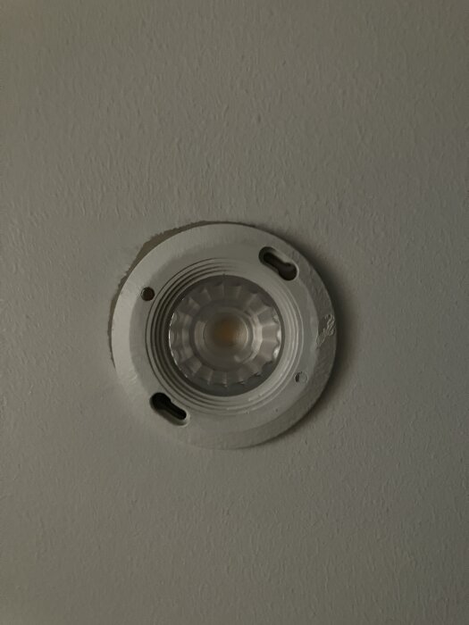 Inbyggd spotlights i badrumstak, demonterad och avstängd, synlig lampa och monteringsfäste ses från undersidan.