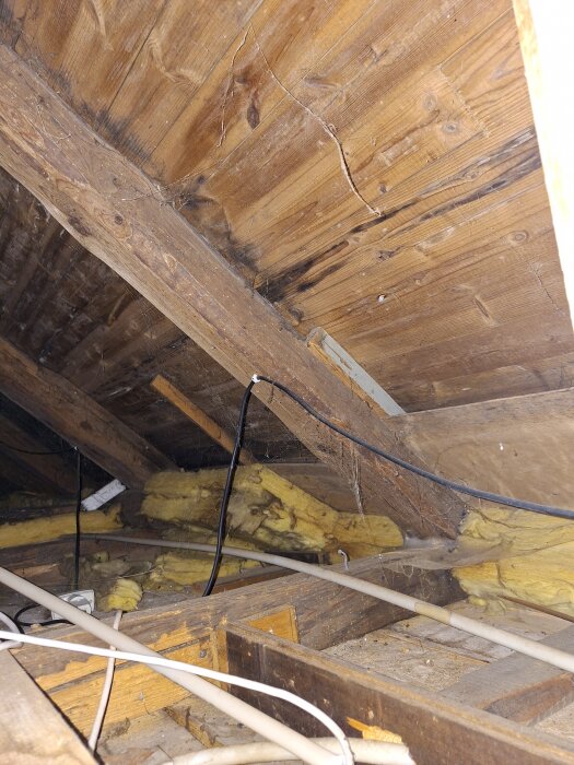 Vind med träbjälkar, isolering och kablar.