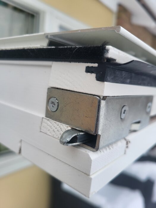 Närbild på ett öppet fönster från Elitfönster, med fokus på metallbeslag och en låsmekanism som inte stänger korrekt.
