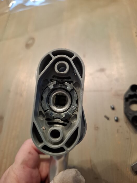 Närbild av ett demonterat handtag från en altandörr, med synliga mekaniska delar inklusive en fjäder och tomt utrymme för små cylindrar.