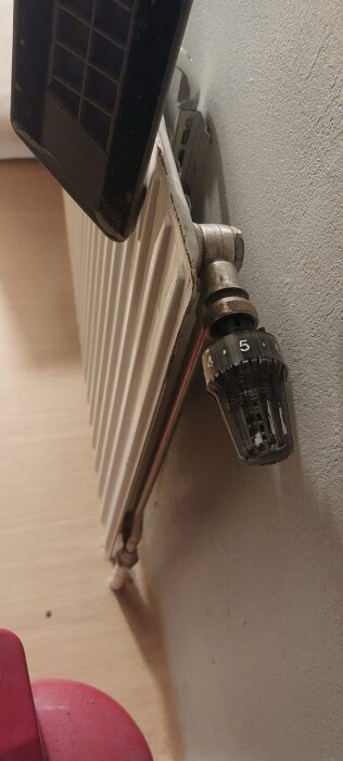 Gammalt radiator med termostatventil, sedd från sidan, monterad mot en vägg. Användaren frågar om rätt koppling för bytet.