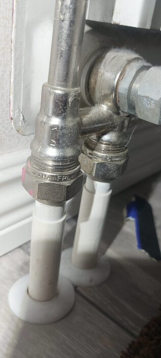 Närbild av metallrör och kopplingar vid ett element, som diskuterar byte och anslutningar, R15 gängdimension nämns i texten.