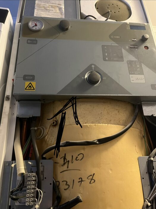 Värmepumpssystem med pilar som markerar läcka; manometer och inkopplade kablar synliga.