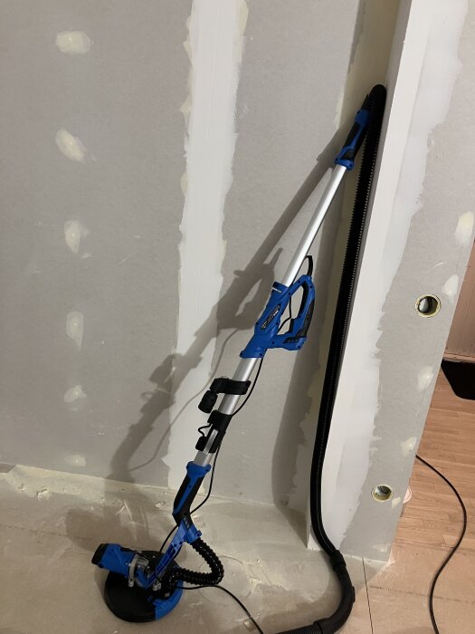 Giraffslip från jem & fix lutar mot en vägg redo för provkörning. Verktyget är blått med svart sladd och stång.