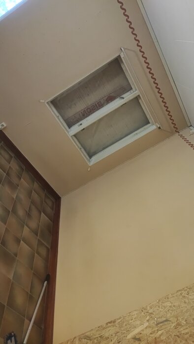 Fastspikat fönster i taket med isoleringsmaterial, del av ett bygg- och renoveringsprojekt.