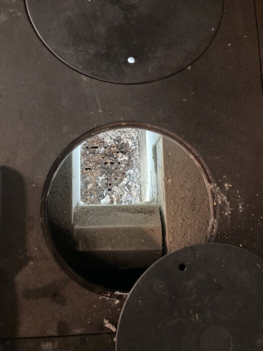 Gammal spishäll med rost och sot i eldstadens ugnsdel.