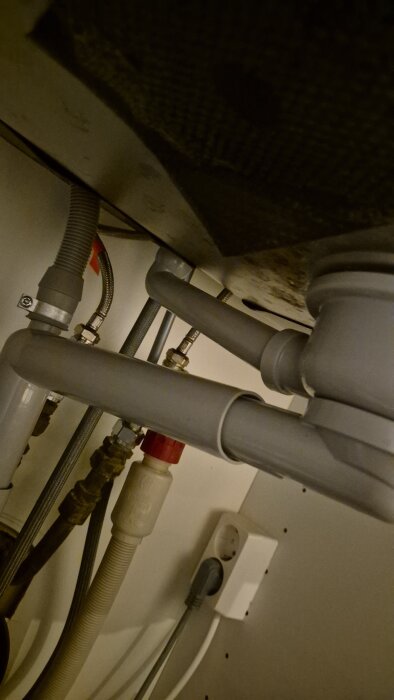 Rör under diskbänk som går från en rörkoppling uppåt. Användaren frågar hur man kan rensa eller öppna det.